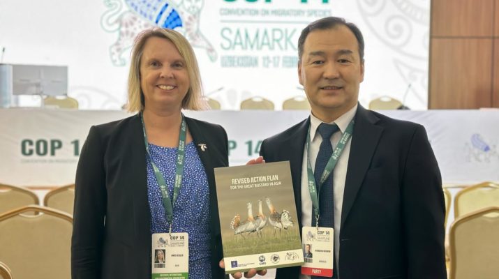 Mimi Kessler and B Nyambayar hold the Revised Action Plan for Great Bustards in Asia, in front of the main stage at CMS COP14